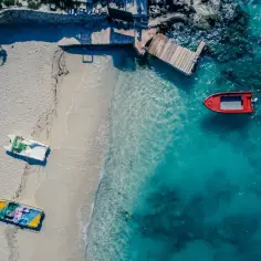 Idealne miejsce, gdzie jest cieplo w styczniu: pusta plaża z łódkami i turkusową wodą.
