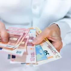 Dłonie trzymające plik banknotów euro. Czy w Czechach można płacić euro? Tak, w wielu miejscach.