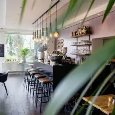 Wnętrze restauracji z barem, stołkami barowymi i stolikami.