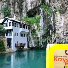 Biały dom nad turkusową wodą u podnóża skalnej jaskini. Idealne miejsce, by zobaczyć Serbię.