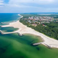 Widok z lotu ptaka na Jarosławiec z plażą, morzem i falochronami. Idealne miejsce na wakacje, zastanawiasz się, jak najlepiej dojechać do Jarosławca?