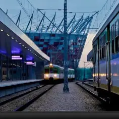 Pociągi na stacji Warszawa Stadion PKP, z nowoczesnym stadionem w tle.
