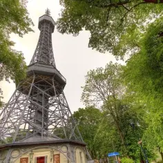 Wieża widokowa w Pradze, przypominająca nieco Wieżę Eiffla, otoczona jest bujną zielenią.