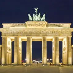 Nocą Brama Brandenburska w Berlinie, oświetlona, z Kwadrygą na szczycie.