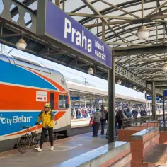 Pociąg do Pragi z Polski czeka na dworcu. Mężczyzna z rowerem gotowy do podróży.