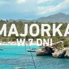 Majorka: co warto zobaczyć? Zatoka z turkusową wodą, plażą, łodziami i skalistymi klifami. Idealne miejsce na wakacje.