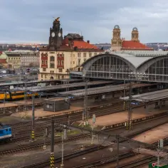 Widok na dworzec główny w Pradze, skąd odjeżdża pociąg do Czech. Widać żółty pociąg RegioJet i niebieski pociąg ČD.