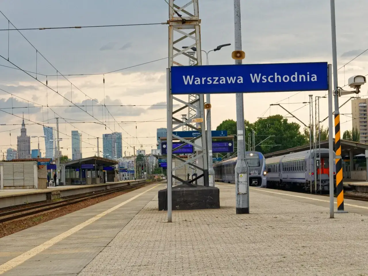 Warszawa Wschodnia, peron 6. Pociąg PKP czeka na pasażerów, w tle widać warszawskie wieżowce.