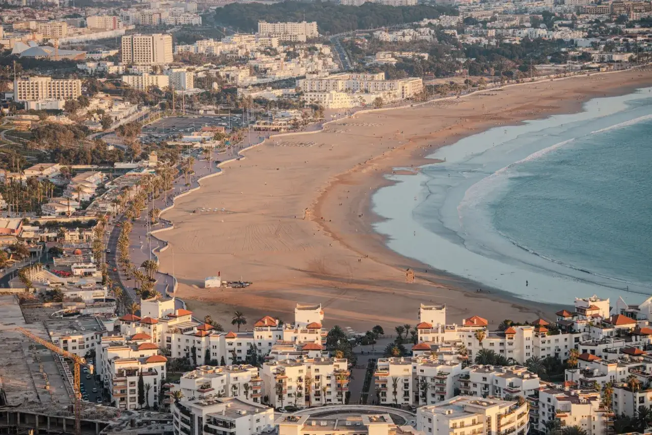 Agadir co zobaczyć: rozległa plaża, ocean i białe budynki z czerwonymi dachami tworzą malowniczy widok.