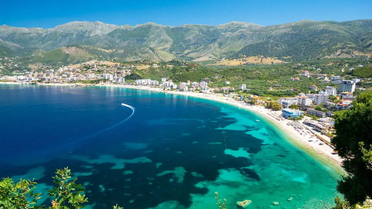Widok na wybrzeże Albanii, z turkusową wodą, piaszczystą plażą i górami w tle. Idealne miejsce, by zobaczyć, co Albania ma do zaoferowania.