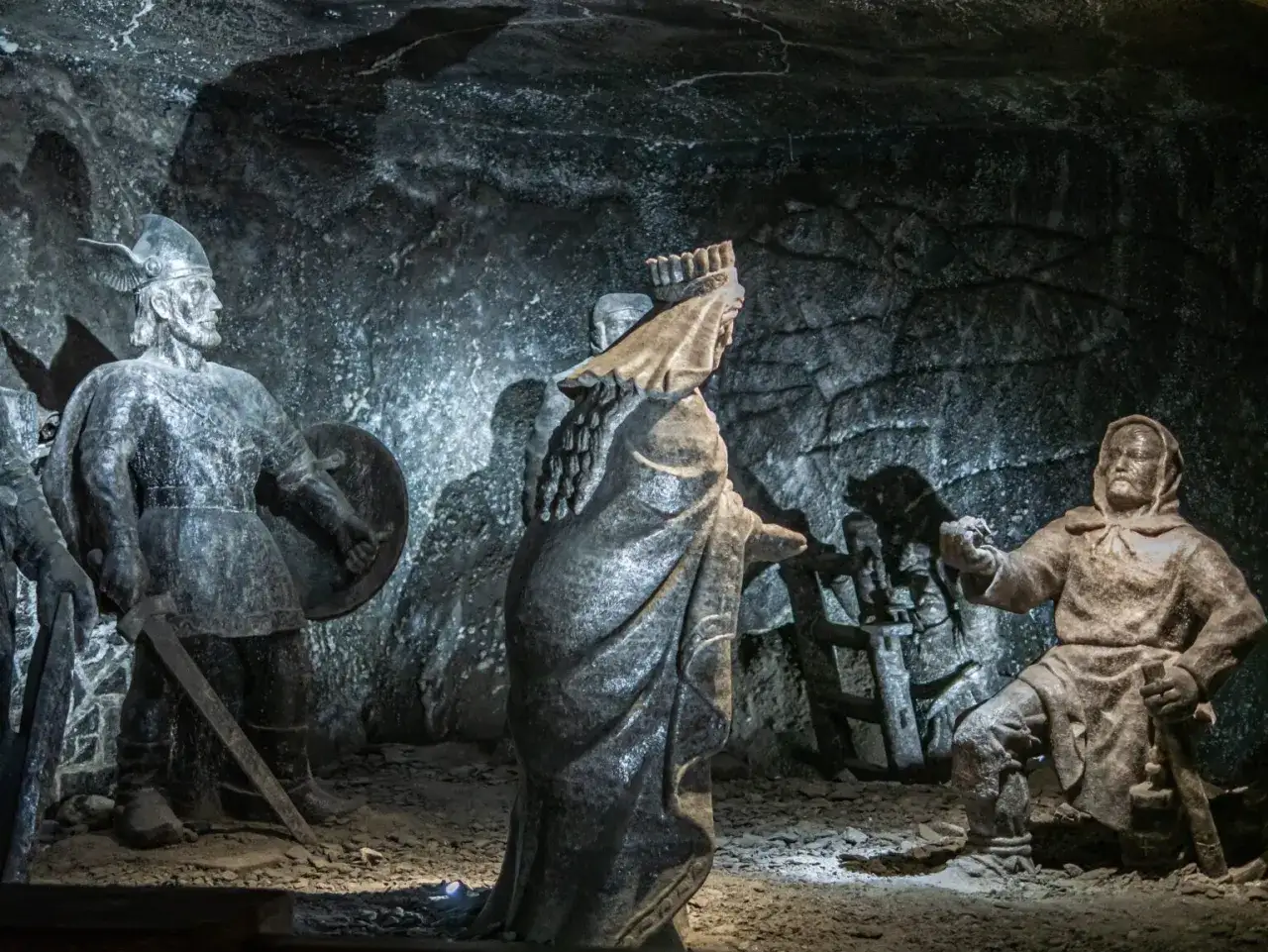 Wieliczka co zobaczyć: rzeźby z soli przedstawiające scenę historyczną. Wojownik z tarczą i mieczem, postać w koronie i klęczący mężczyzna.