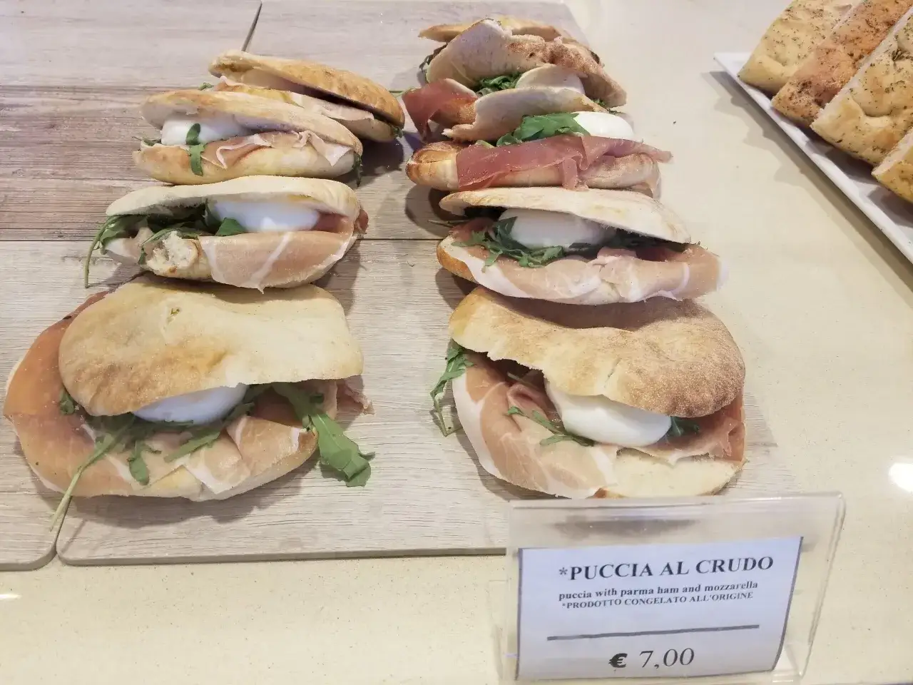 Pyszne puccie z szynką parmeńską i mozzarellą, idealne na szybki lunch. Ceny jedzenia we Włoszech bywają różne, ale ta wygląda na wartą swojej ceny 7 euro.