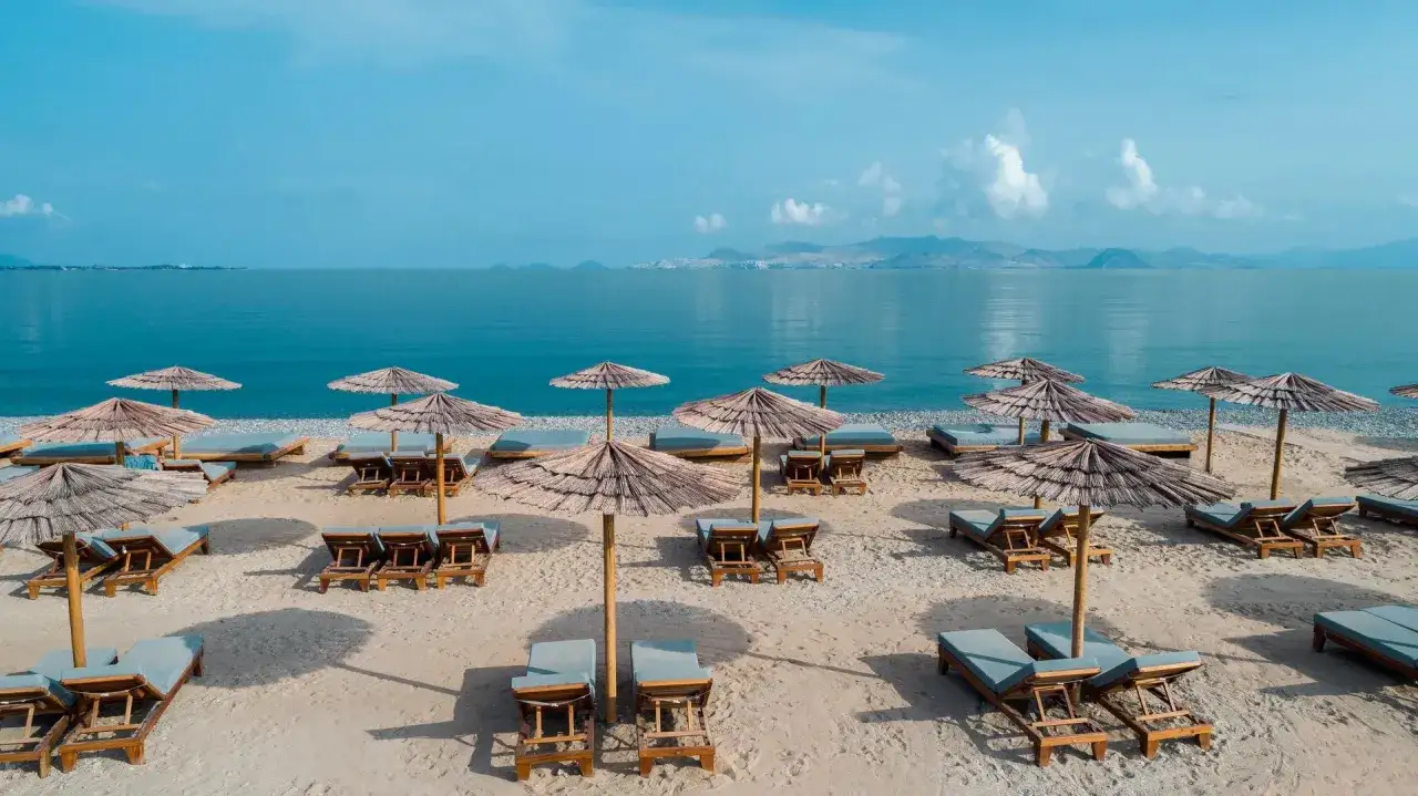 Plaża na wyspie Kos z leżakami i parasolami. Idealne miejsce na relaks i podziwianie widoków.