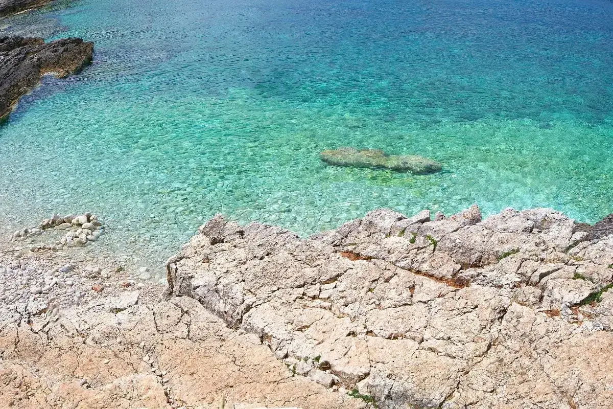 Idealne miejsce, gdzie na wakacje w sierpniu: skalista plaża i krystalicznie czysta, turkusowa woda.