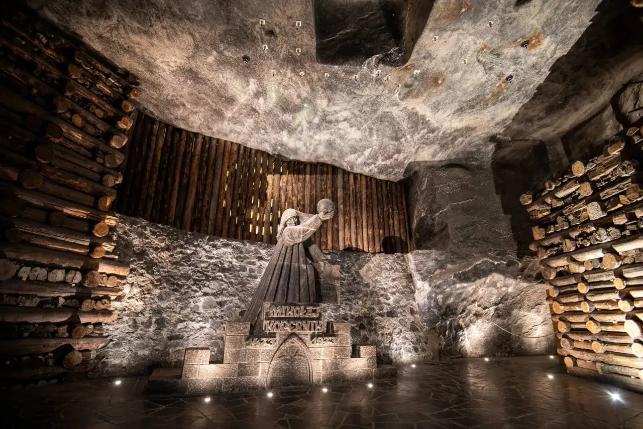 Wieliczka co zobaczyć: rzeźba Mikołaja Kopernika w kopalni soli, otoczona drewnianymi belkami i solnymi ścianami.