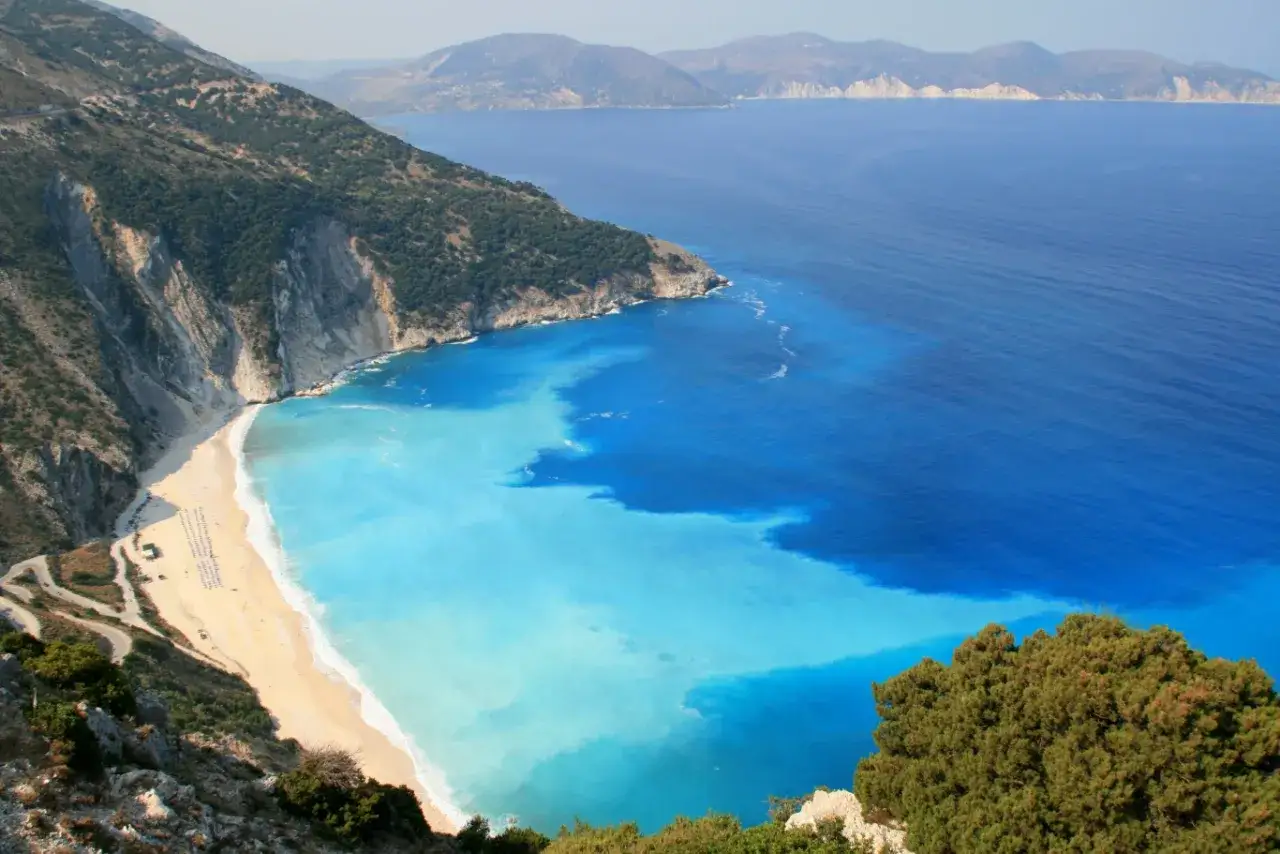 Widok na plażę Myrtos na greckiej wyspie Kefalonia. Turkusowa woda miesza się z głębokim błękitem morza.