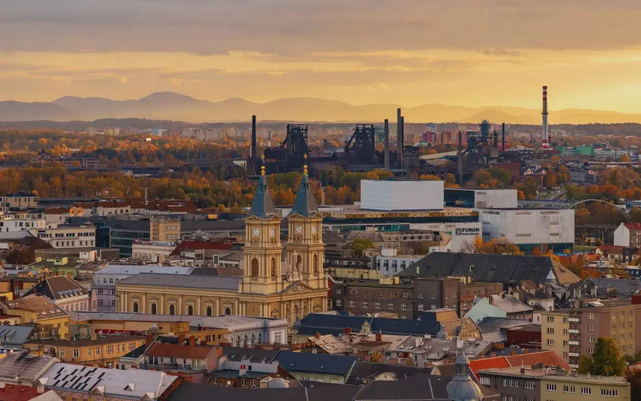 Zachód słońca nad Ostrawą. Widać zabytkowy kościół, nowoczesne centrum Forum Nova Karolina i przemysłowe hutnicze dziedzictwo. Ostrawa co zobaczyć to połączenie historii i nowoczesności.