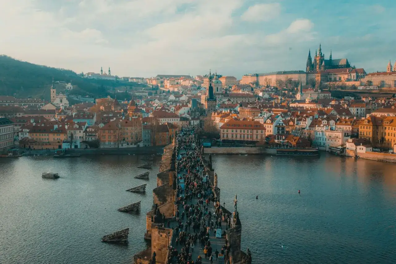 Tłum ludzi na Moście Karola w Pradze, z widokiem na miasto i zamek. Wspaniałe punkty widokowe Praga oferują niezapomniane wrażenia.